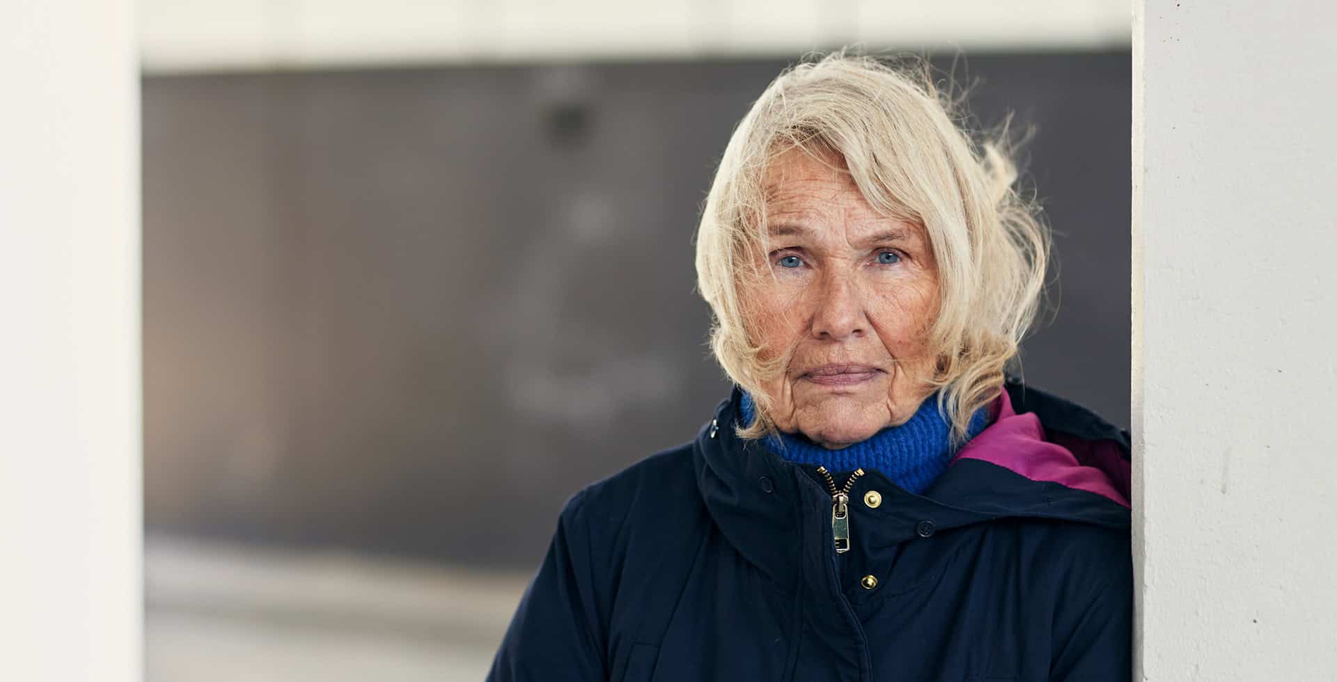 Porträtt av en äldre dam som blickar in mot kameran.