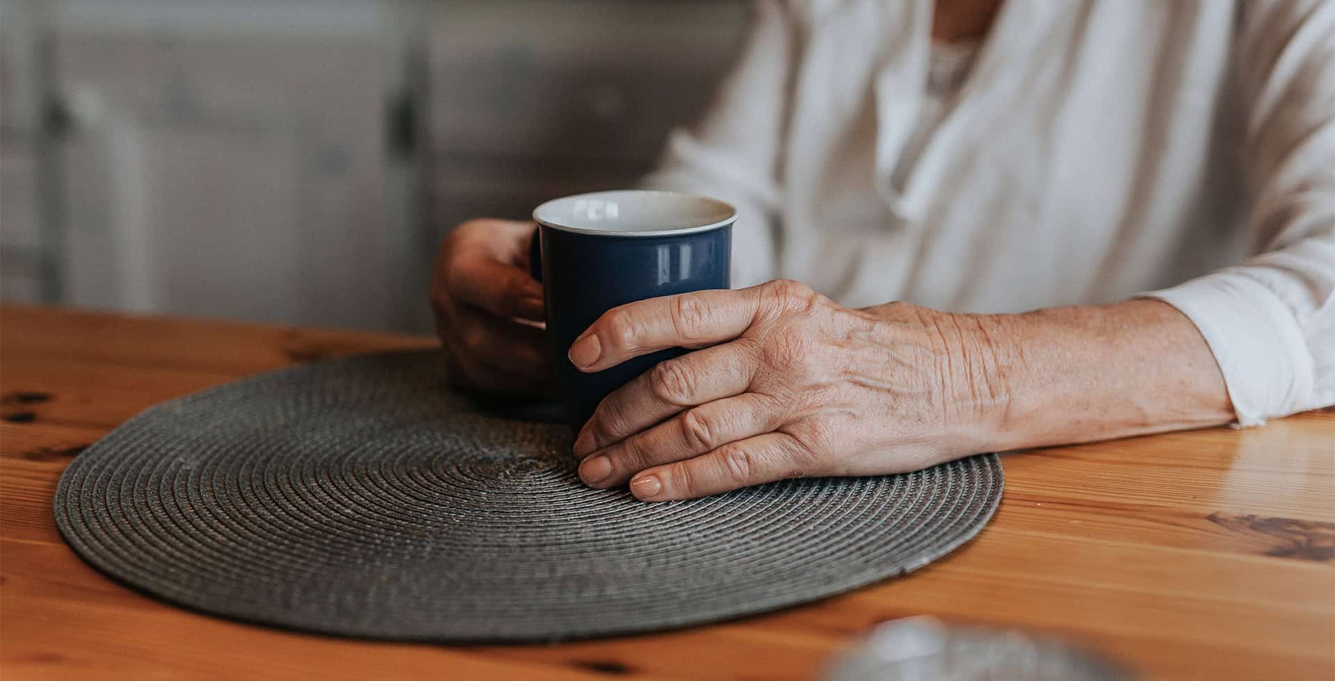 Äldre persons händer håller i en kaffekopp.