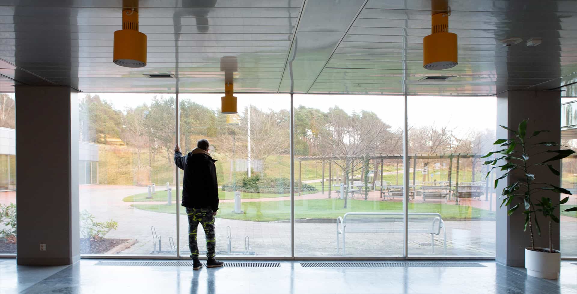 Niklas står ett stort rum och blickar ut genom stora fönster.