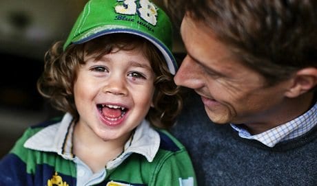 Axel sitter i knät på sin pappa Per och ler glatt.