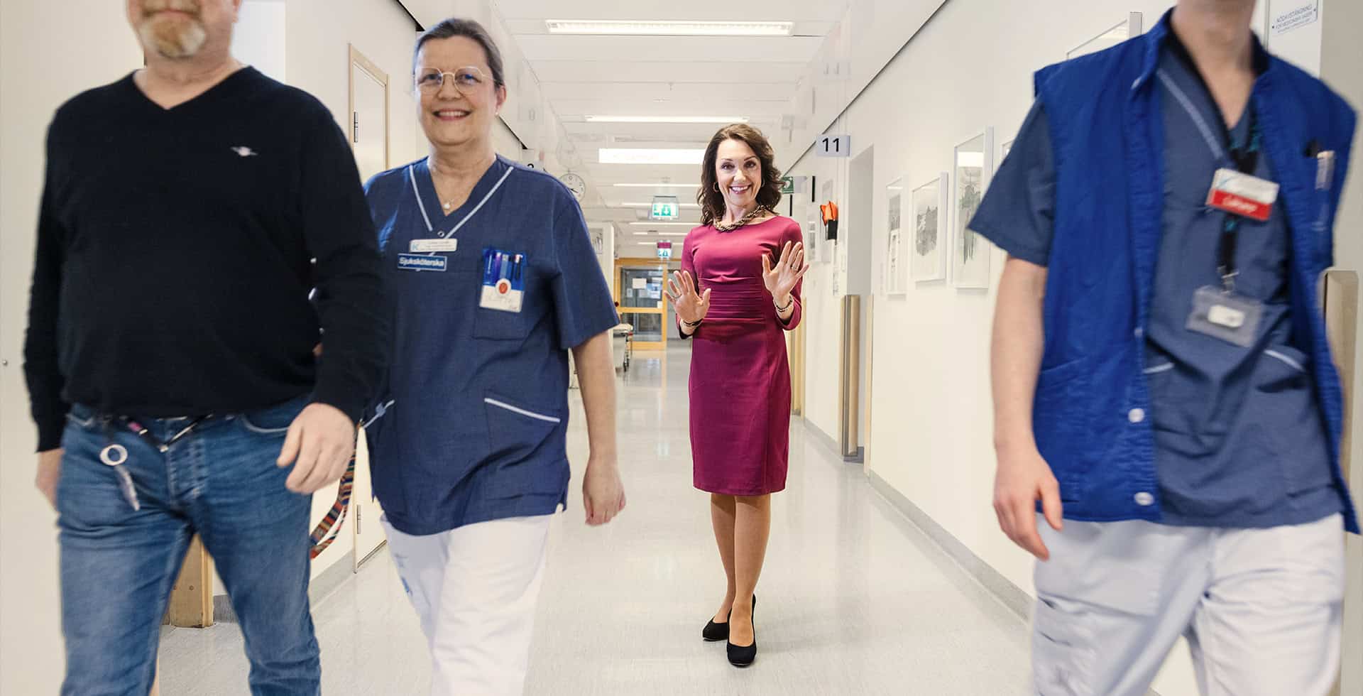 Professor Miia Kivipelto står i en korridor i ett sjukhus och ler mot kameran.