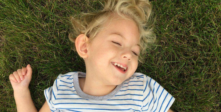 Porträtt av My när hon ligger i gräset och ler.