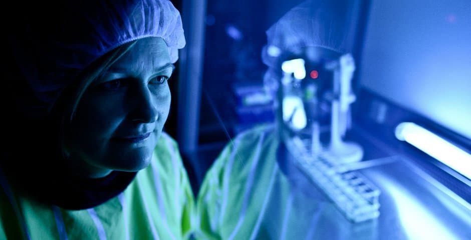 Malin Parmar i ett cell-labb i skyddskläder och ett blått ljus.