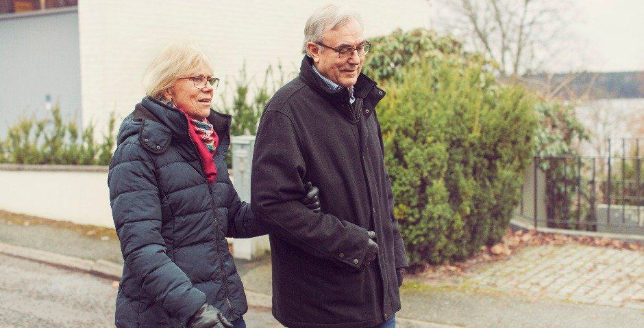 Ett äldre par promenerar utomhus.