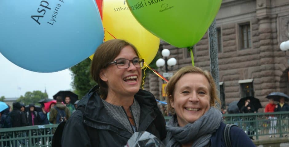 Anna Hemlin och Lena Dahlenborg står utomhus med färgglada ballonger under Hjärnfondens manifestation.