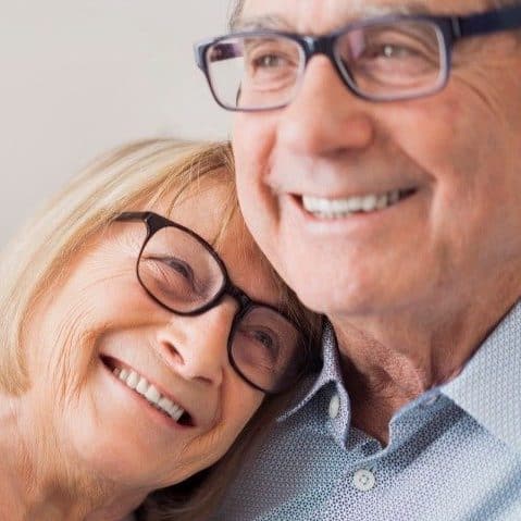 Ett äldre par kramar om varandra och ler glatt.