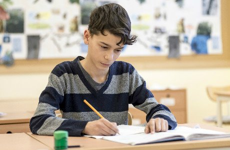 Elev sitter vid en skolbänk och pluggar.