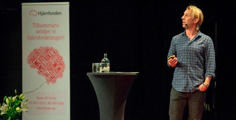 Anders Hansen står på scen och talar i en mikrofon.