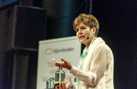 Ulla Karin står på en scen och talar i en mikrofon.