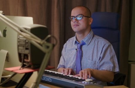 Alexander spelar på ett elektronisk piano vid sin dator.