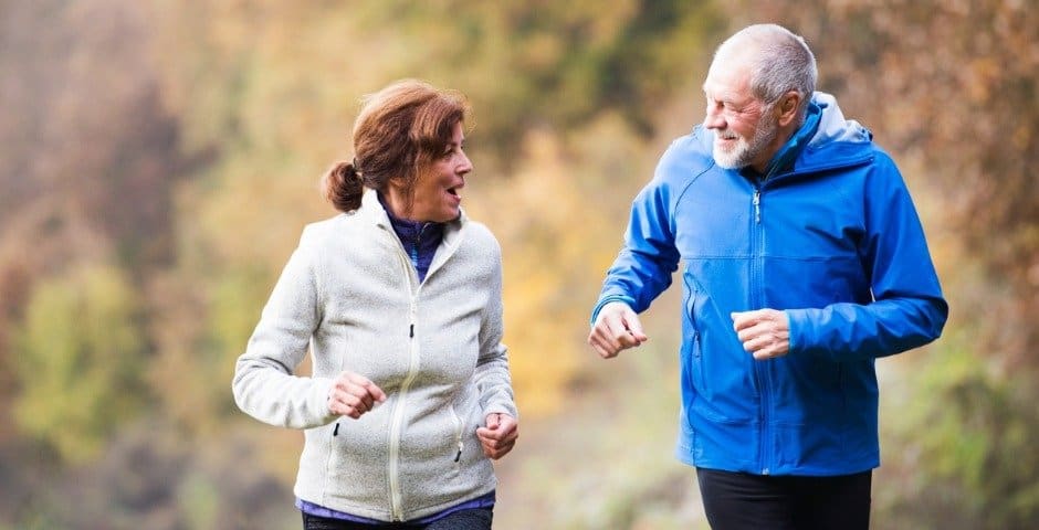 Två äldre personer är ute och joggar.