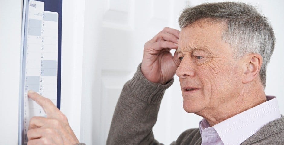 Äldre man kliar sig på huvudet och har fingret på en kalender.