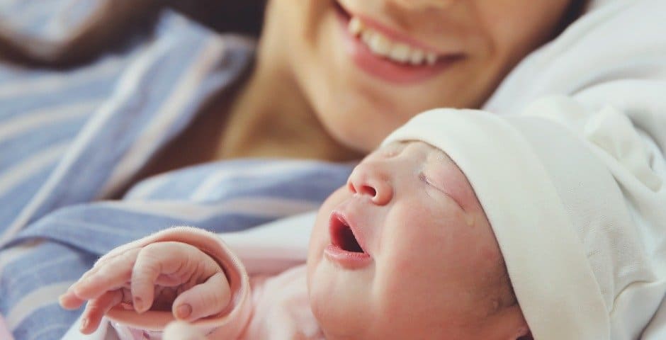 Nyfödd bebis ligger med sin mamma i en säng.