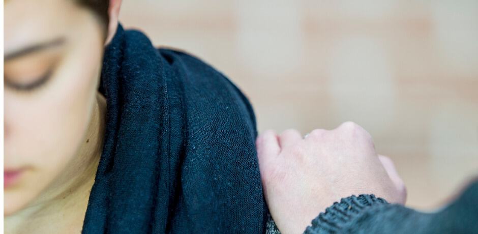 En ung tjej med en person hand på sin axel.