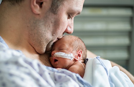 Pappa håller sitt för tidigt födda barn in till sig.