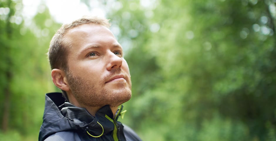 En man står i naturen och tittar uppåt.