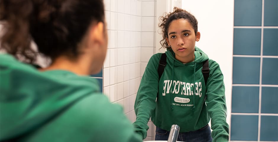 Orolig flicka tittar sig i spegeln.