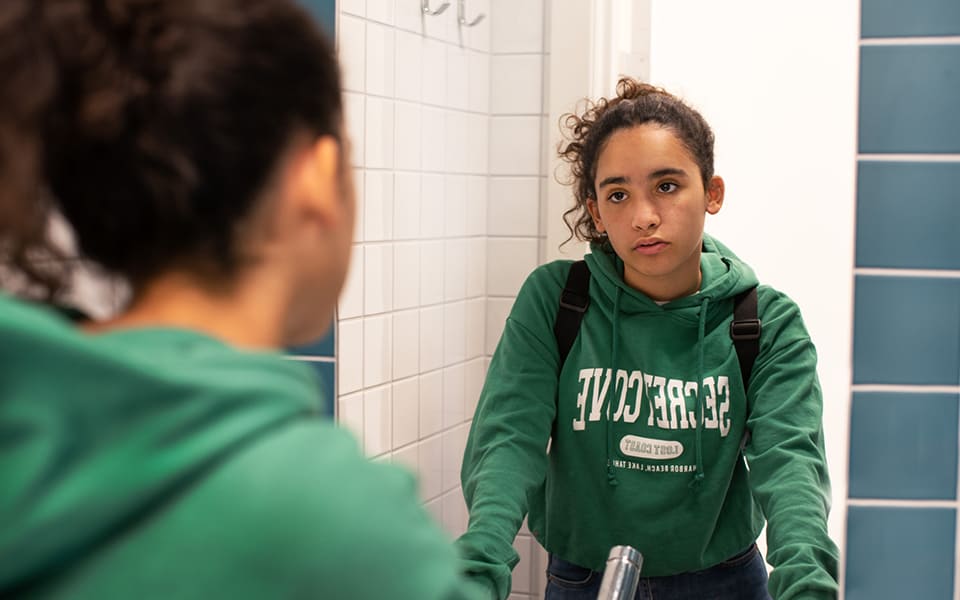 Deppad tjej ser sig i spegeln på toaletten.