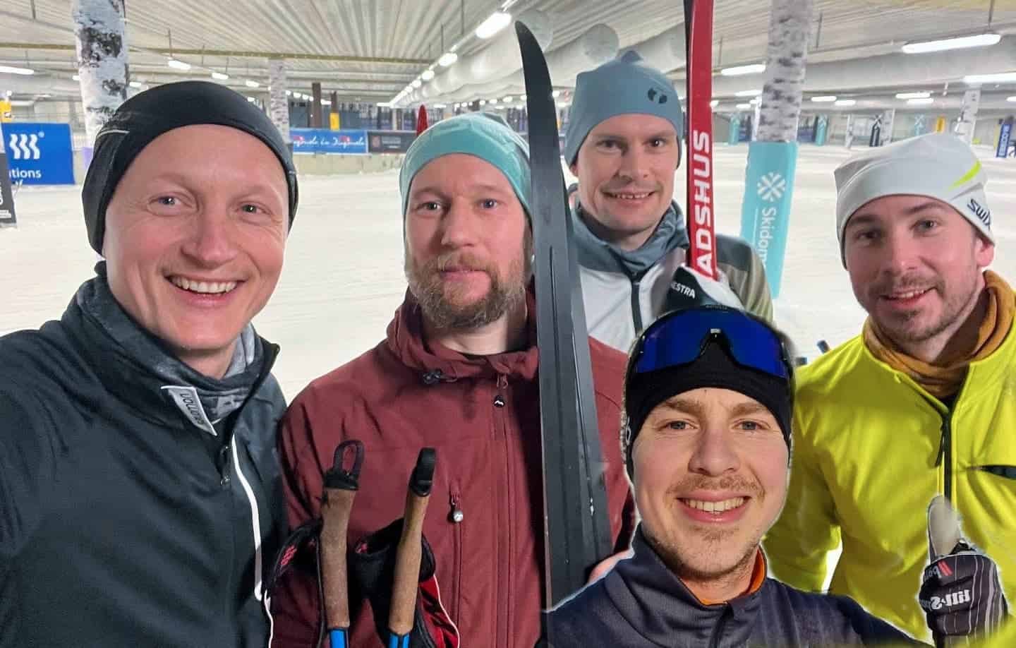 Fem män poserar i vinterkläder och längdskidor.