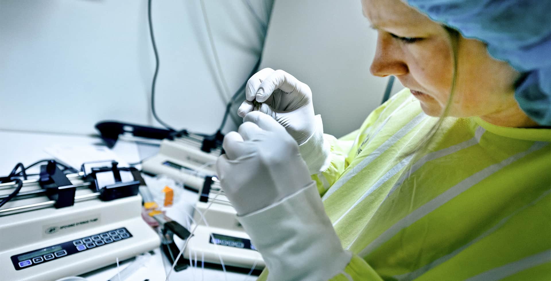 Forskare i skyddskläder arbetar koncentrerat med ett prov i laboratoriemiljö.