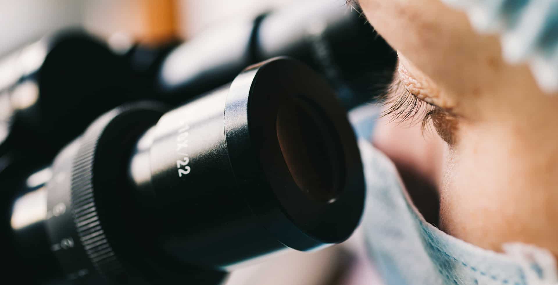 Närbild på en forskare som tittar in i ett mikroskop.