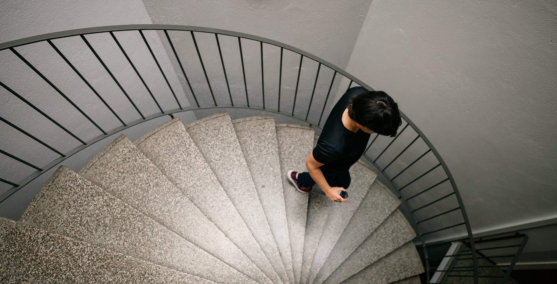 En ung person går ner för en spiral trappa.