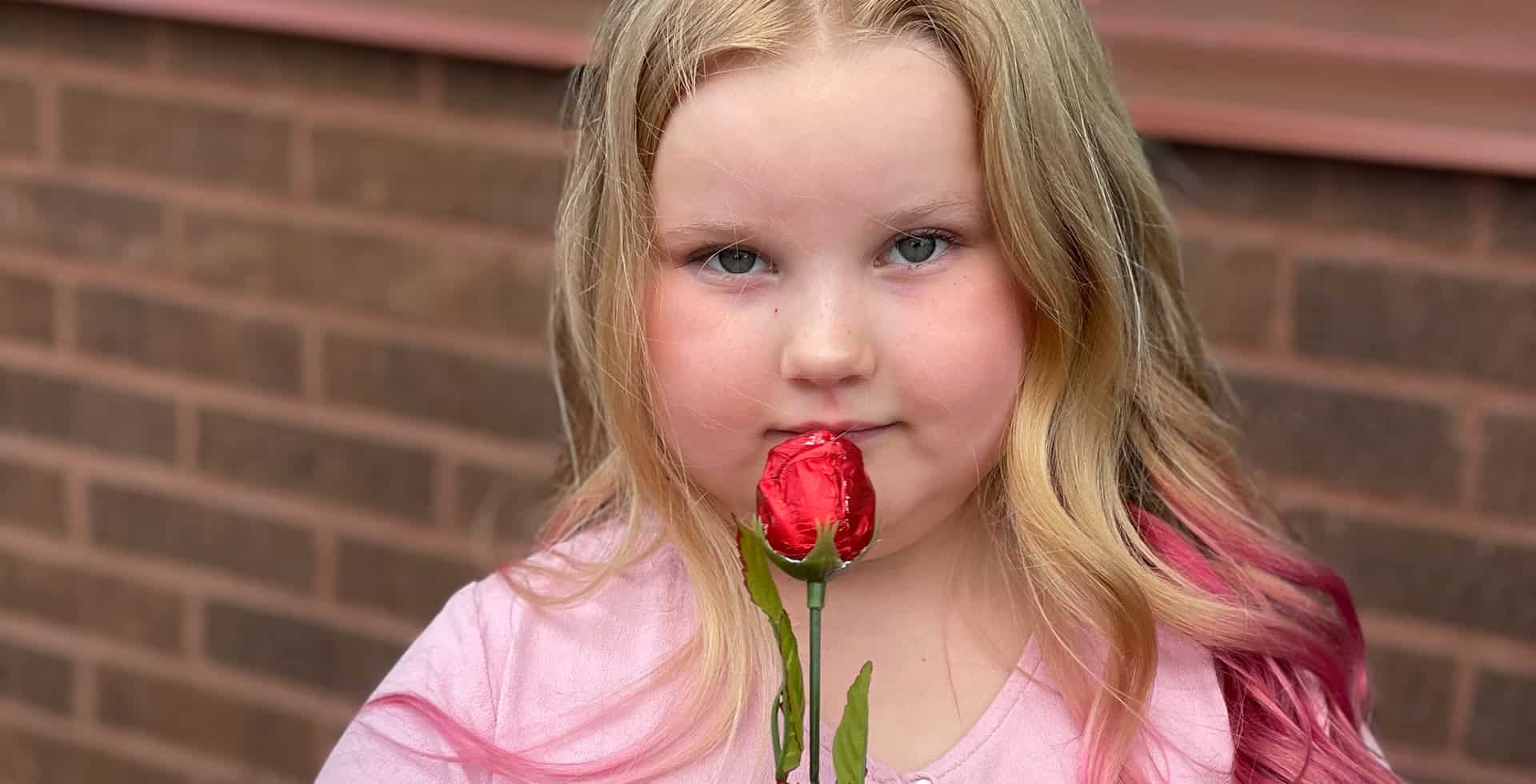 Porträtt av Hedda som står med en röd ros.