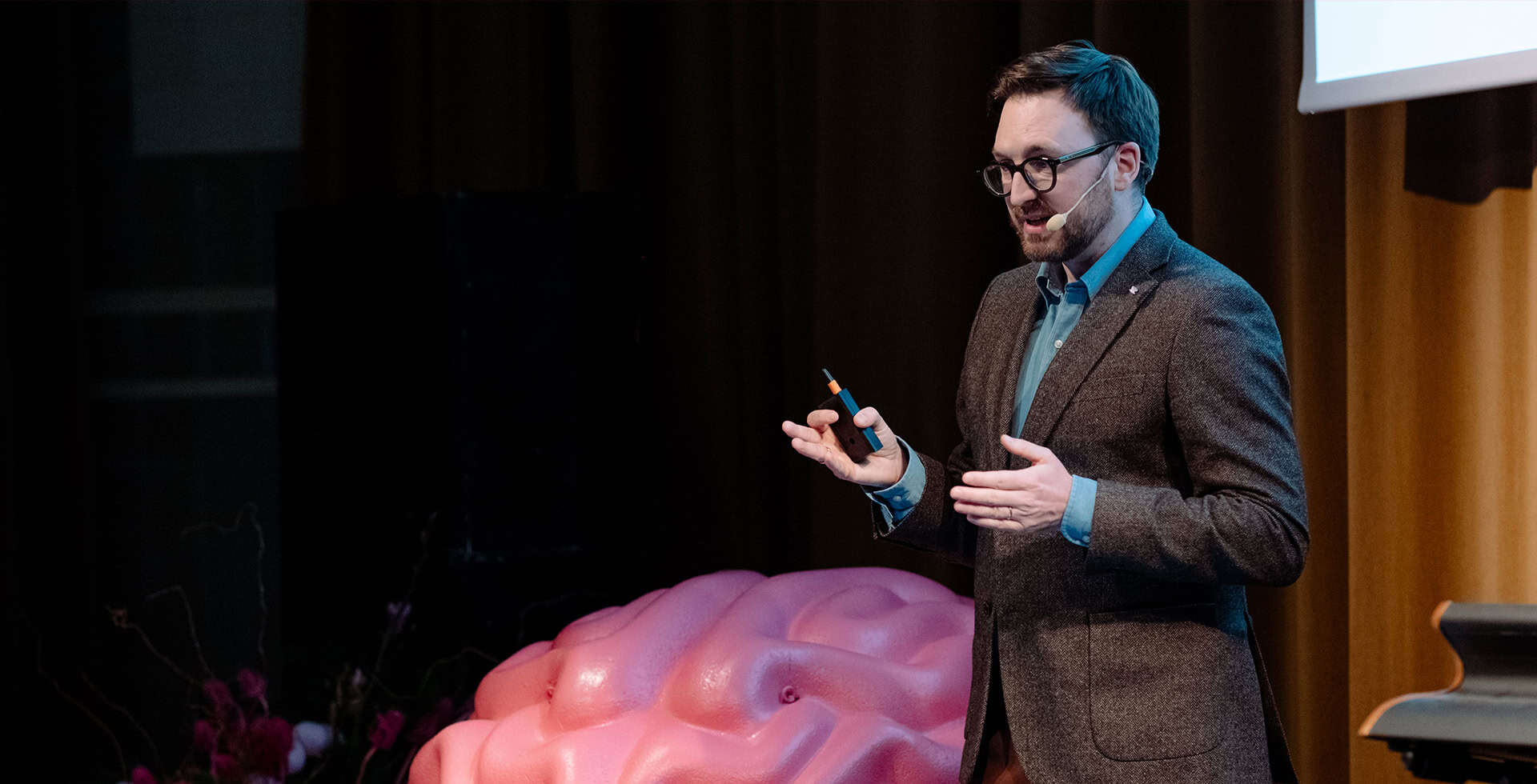 Micheal Schöll talar på en scen i en mikrofon.