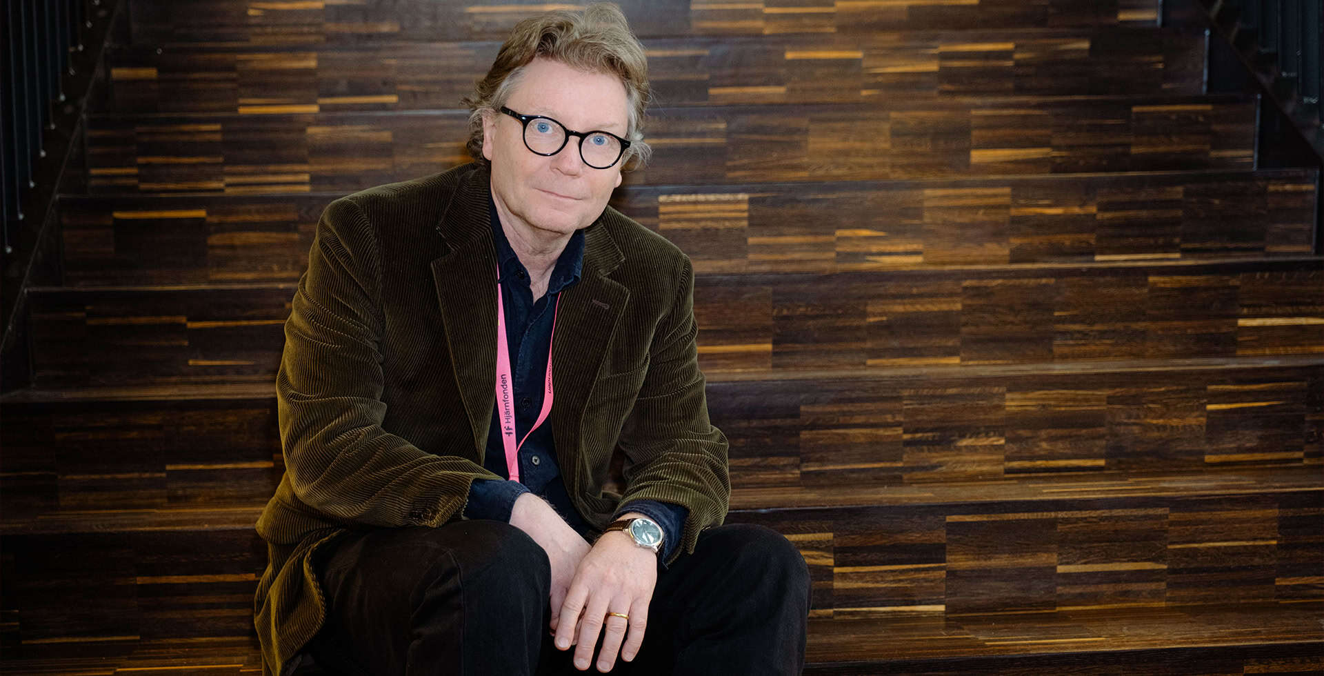Porträtt av Janne Johansson som sitter i en trappa.